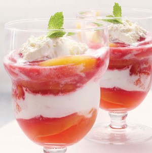 Two glasses with parfait, topped with a peach and mint