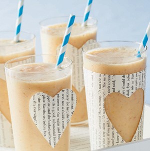 Tall glasses filled with smoothie and topped with a blue and white stripped straw and cut-out newspaper hearts