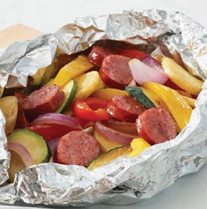 Aluminum pouch filled with sausage, sliced zucchini, red onions, bell peppers, and yellow summer squash