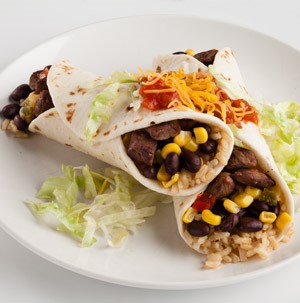 Two flour tortillas wrapped around chopped cooked beef, rice, corn, and black beans topped with salsa and shredded cheese