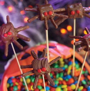 Chocolate-covered marshmallows and pretzel sticks, shaped into a spider and decorated with cinnamon red hot candies