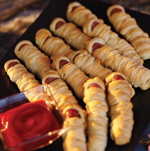 Hot dogs wrapped in pastry with a side of ketchup
