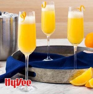 Champagne flutes filled with mimosas and garnished with orange peels