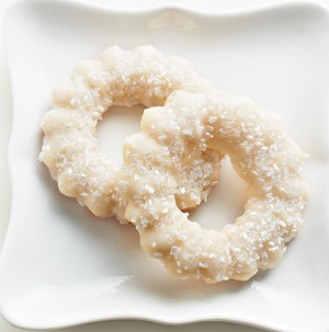 Spritz cookies on a white serving platter with coarse white sugar on top