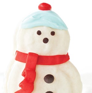 Macaroons decorated like snowmen with a red scarf and blue frosting hat