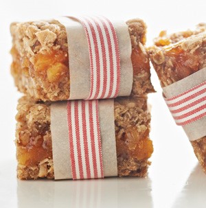 Apricot bars stacked and wrapped in parchment paper and red-and-white striped ribbon