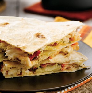 Plate of stacked quesadillas filled with Alaskan crab and artichoke