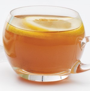 Clear mug of apricot-apple cider topped with lemon slices