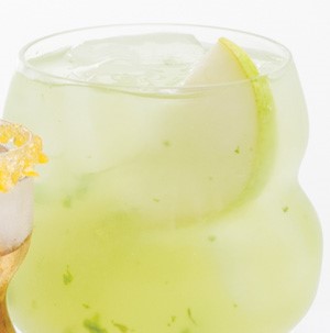 Yellow spritzer in a clear glass with ice and pear slice