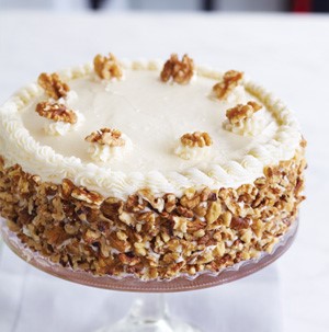 White frosted cake topped with walnuts on a cake stand