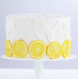 Vanilla frosted cake on a cake stand garnished with lemon slices