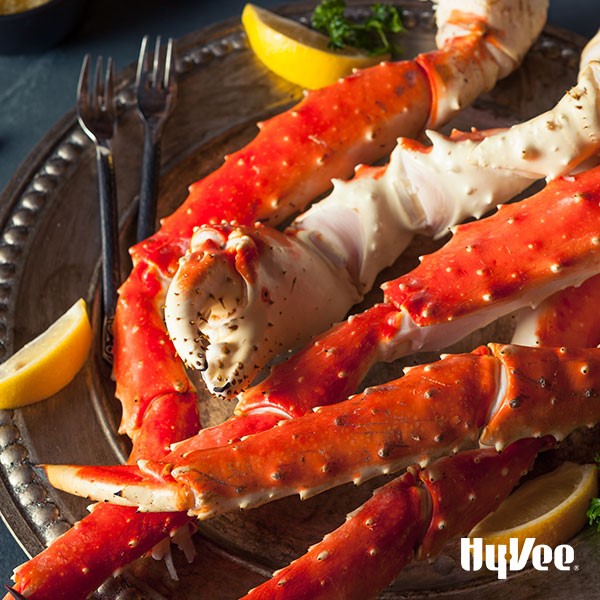 Platter of Alaska crab legs with lemon wedges and eating utensils 