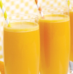 Glass filled with orange drink and topped with orange, yellow and white striped straws