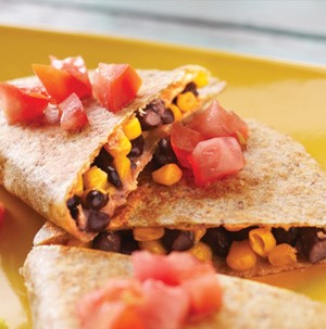 Plate of black bean and corn quesadillas topped with fresh tomato