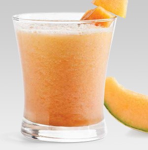 Glass of orange-colored smoothie, garnished with cantaloupe