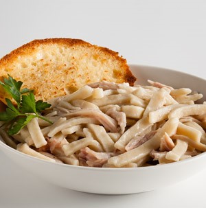 Creamy wide noodles with shredded chicken topped with Italian parsley and toasted bread