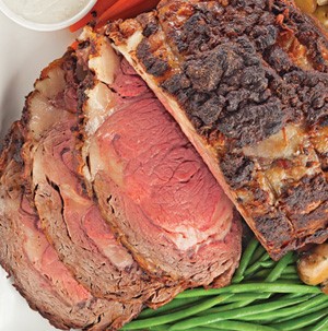 Partially sliced prime rib roast served with side of fresh green beans