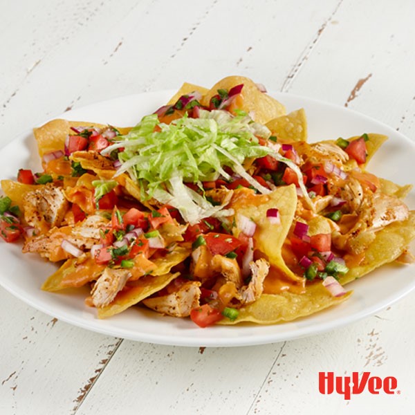 Tortilla chips topped with shredded chicken, diced tomatoes, peppers, and red onion and topped with cheese and shredded lettuce