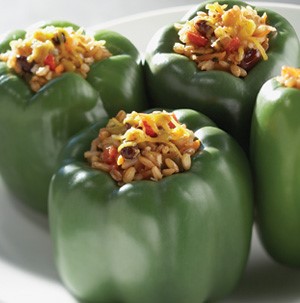 Four green peppers stuffed with rice, beans, and topped with melted shredded cheese