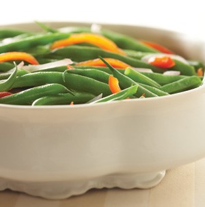 Casserole dish filled with shallots, fresh green beans, and sliced bell peppers