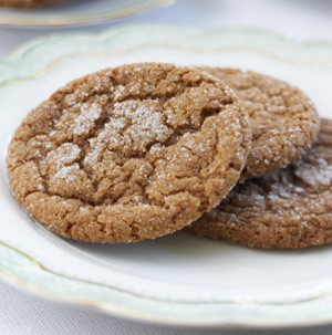 Three stacked ginger molasses crackle cookies with a dusting of powdered sugar on top