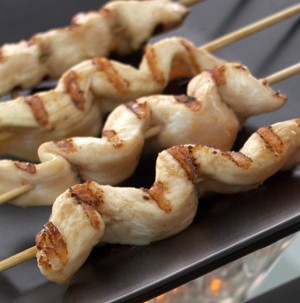 Thin slices of grilled chicken on wooden skewers
