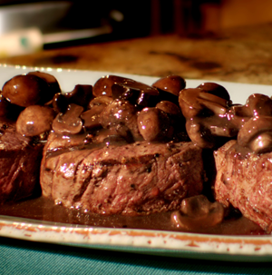 Grilled filet mignons topped with sliced mushrooms and red wine sauce