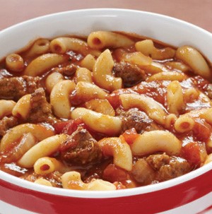 White and red bowl holding bowl of goulash with elbow macaroni