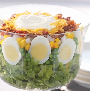 Lettuce stacked with celery, egg slices, peas, green bell pepper, onion and bacon