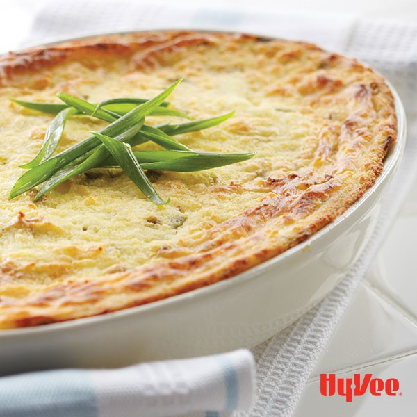 White casserole dish with baked mashed potatoes and sliced green onions on top