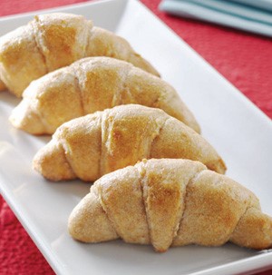 Four crescent rolls on a white platter