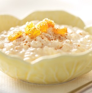 Bowl of creamy rice pudding topped with cinnamon and rum-soaked raisins