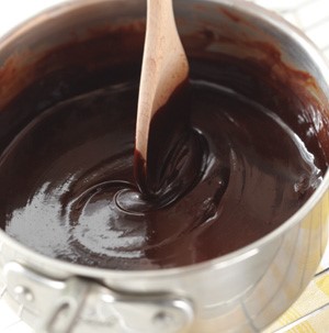 Pot of chocolate sauce with wooden spoon