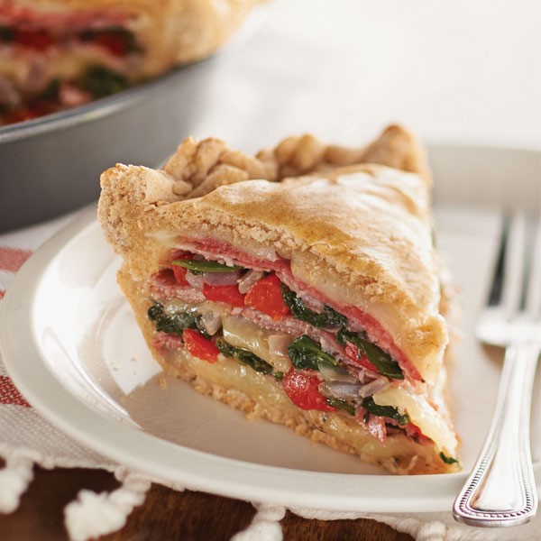 Two crust pie filled with cheese, ham, tomatoes, and spinach