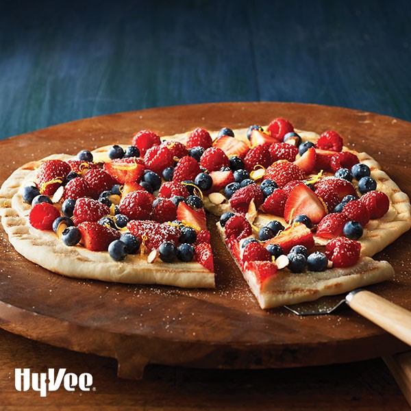 Grilled pizza crust topped with mixed berries, lemon zest, and dusted with powdered sugar