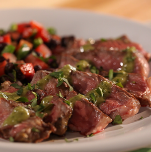 Sliced rib eye steak topped with green chili-lime dressing with side of chopped tomatoes, peppers, and black beans