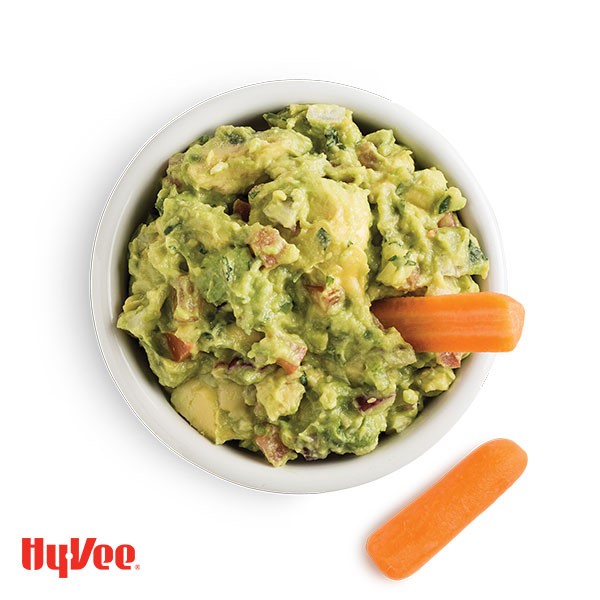 Bowl of chunky guacamole with carrot sticks