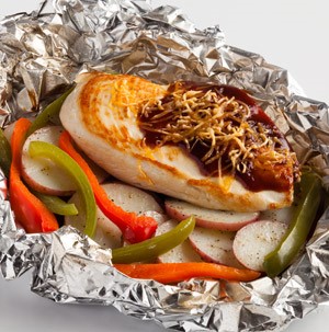 Aluminum foil filled with BBQ cheddar chicken, radishes and red and green bell peppers