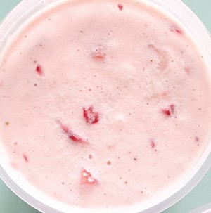 Bowl of pink strawberry ice cream filled with fresh strawberry chunks