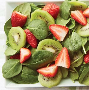 Spinach mixed with sliced stawberries and sliced kiwi