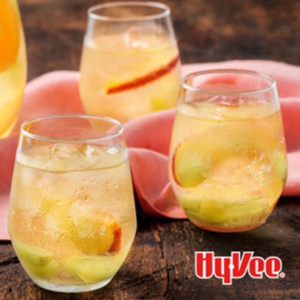 White sangria in glasses with peach slices and pink napkin