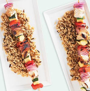 Platter of chicken and vegetable kabobs over rice