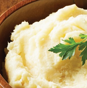 Mashed parsnips in a wooden bowl garnished with fresh Italian parsley