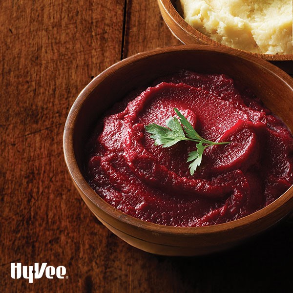 Wooden bowl of beet, turnip and potato mash, garnished with parsley leaf