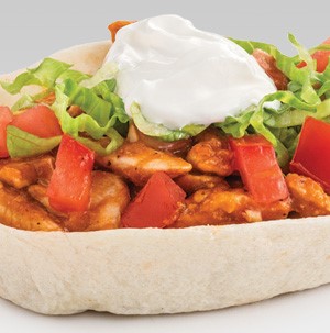 Flour taco bowls packed with chicken, chopped tomatoes, shredded lettuce, and dollop of sour cream