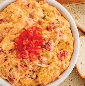 Buffalo chicken dip in a white bowl topped with diced tomatoes