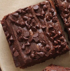 Black bean brownie squares on parchment paper topped with mini chocolate chips