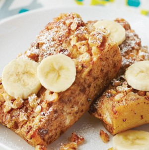 Plate of brie-stuffed banana french toast garnished with banana slices, pecans and sprinkles of powdered sugar