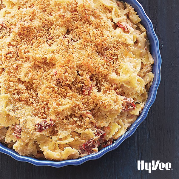 Blue bowl filled with cheesy bow tie pasta and bread crumb topping