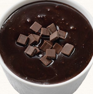Cup of chocolate dip with chocolate cubes floating in the center